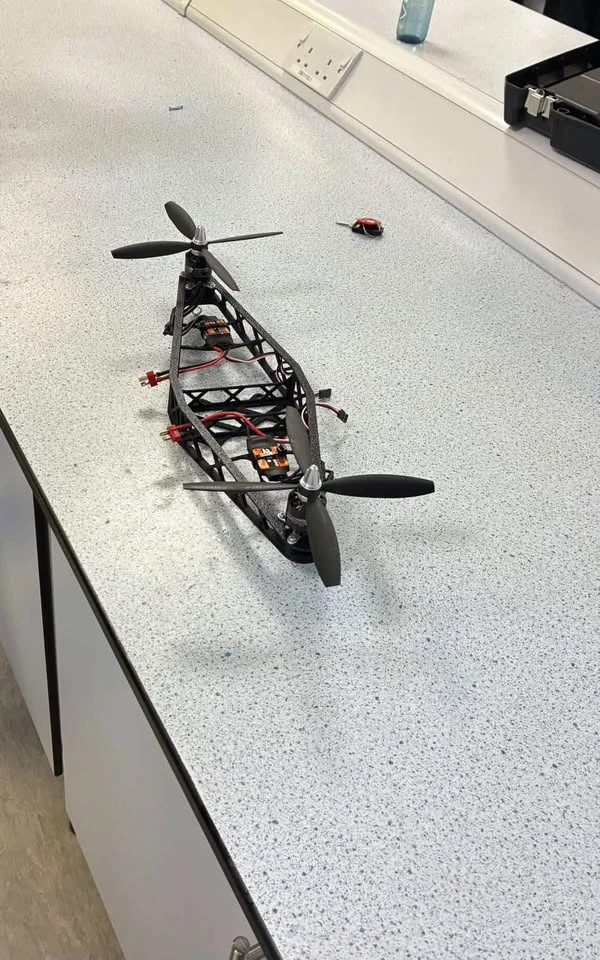 Built printed airframe with propellers and electronics on a bench.